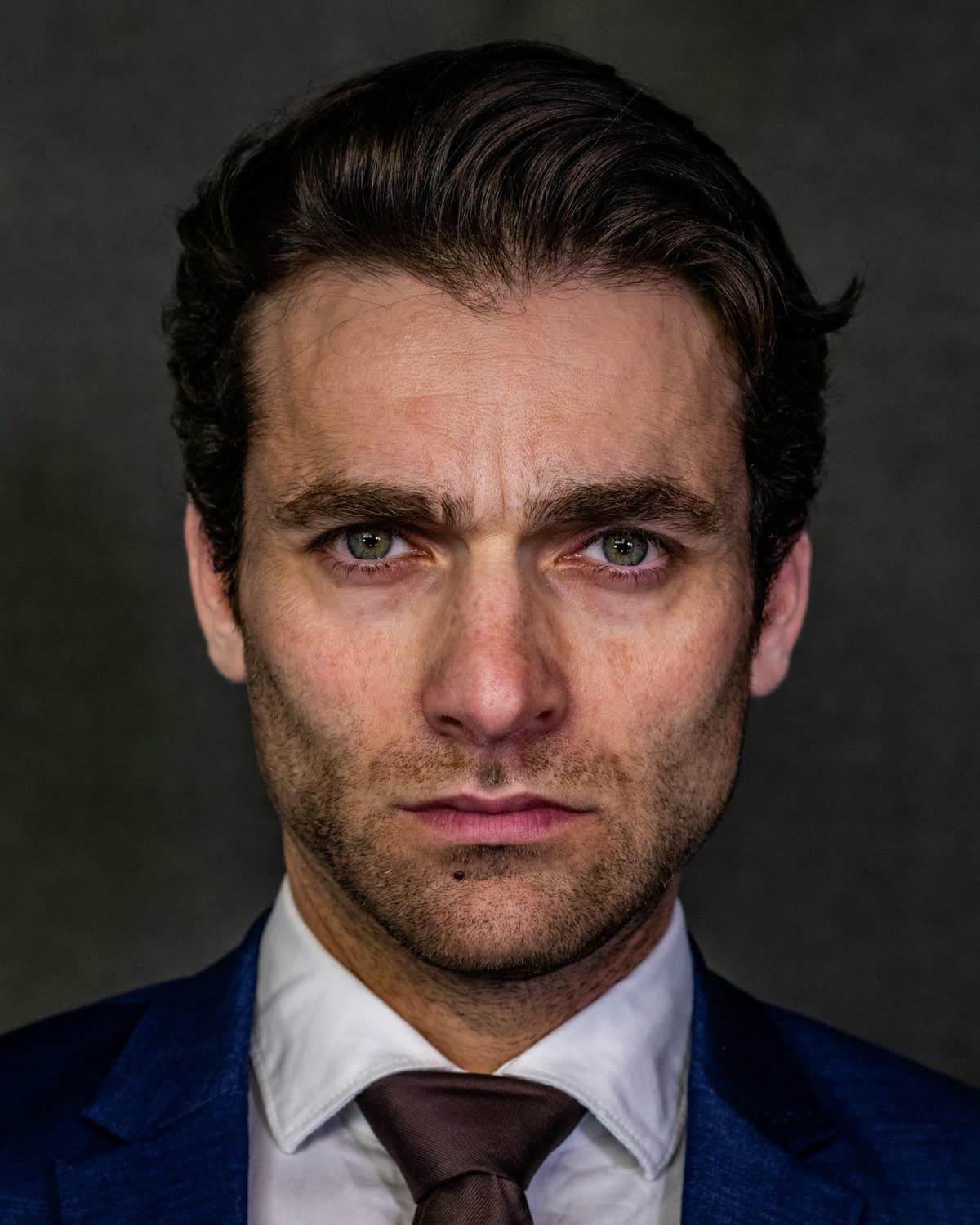 A composed executive in a dark, considered portrait.